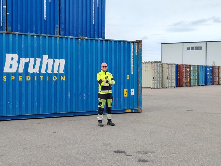 Miikka Turkia seisoo sinisen kontin edessä konttiterminaalilla.